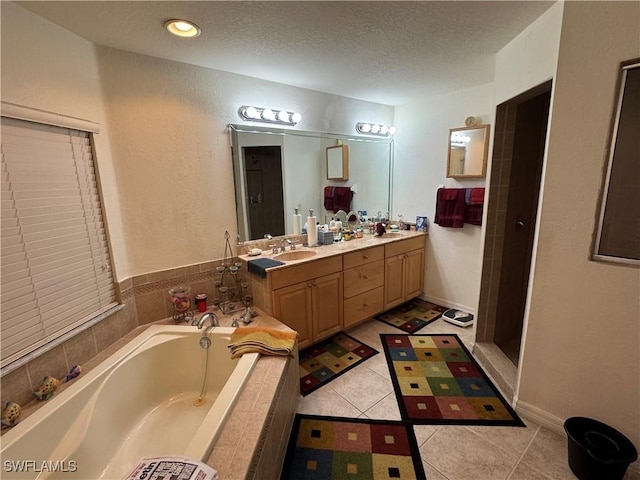 full bath featuring double vanity, tile patterned floors, a garden tub, a textured ceiling, and a sink