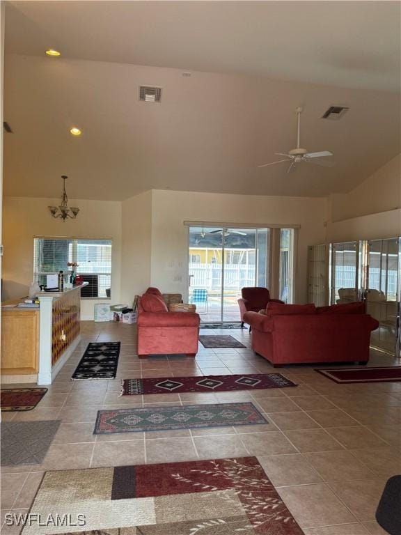 living area with high vaulted ceiling, tile patterned flooring, visible vents, and ceiling fan with notable chandelier