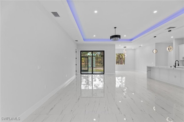 unfurnished living room featuring baseboards, visible vents, a raised ceiling, a sink, and recessed lighting