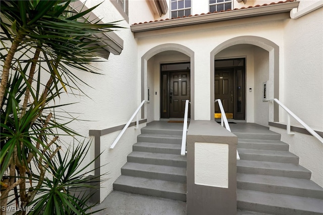 property entrance featuring a tiled roof and stucco siding