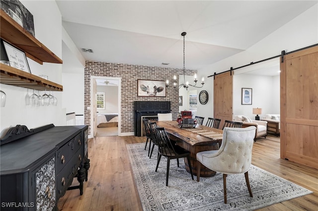 dining space featuring visible vents, brick wall, a barn door, and light wood-style flooring