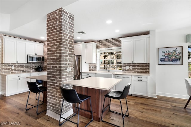 kitchen featuring stainless steel appliances, a kitchen island, light countertops, and white cabinets