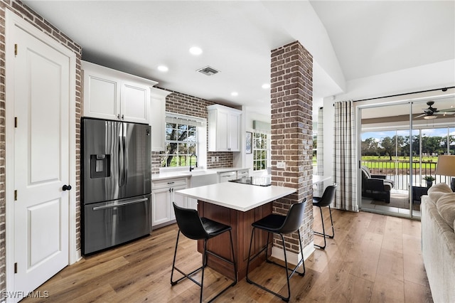 kitchen featuring a breakfast bar, light countertops, visible vents, white cabinets, and stainless steel fridge