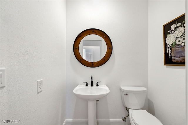 bathroom with toilet and baseboards