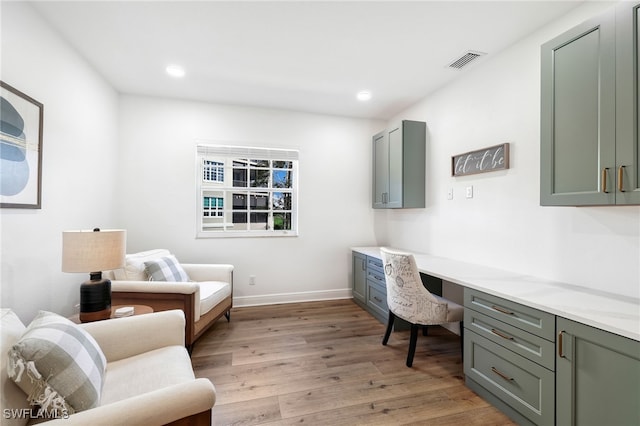 home office with light wood finished floors, baseboards, visible vents, built in desk, and recessed lighting