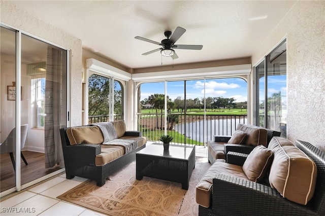 sunroom featuring ceiling fan, a water view, and a wealth of natural light