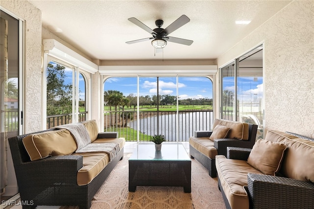 sunroom / solarium with a water view, plenty of natural light, and a ceiling fan