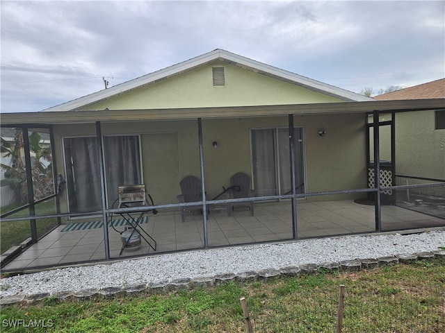 back of property with a sunroom, a patio, and stucco siding