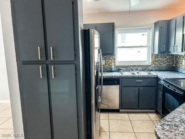 kitchen with light tile patterned floors, appliances with stainless steel finishes, decorative backsplash, and a sink