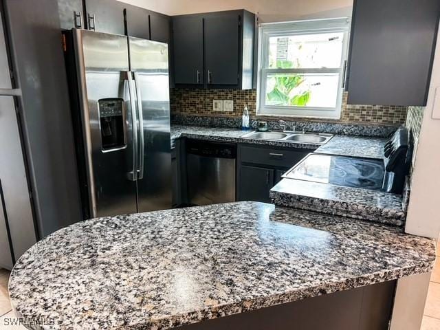 kitchen featuring light tile patterned floors, decorative backsplash, dark stone countertops, stainless steel appliances, and a sink