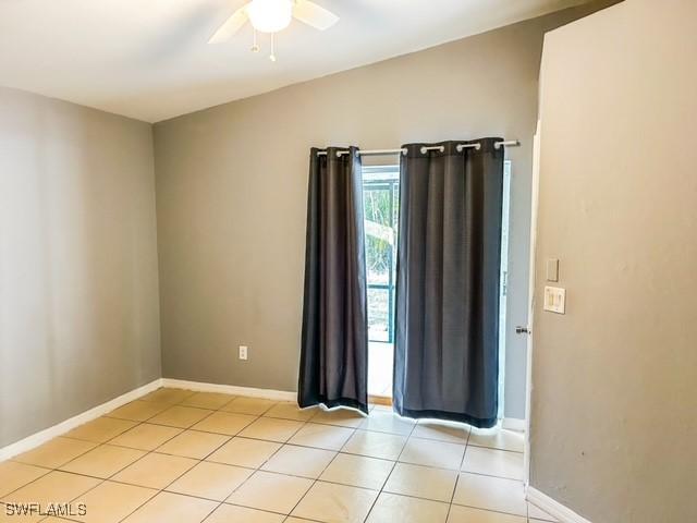 spare room with lofted ceiling, light tile patterned floors, ceiling fan, and baseboards