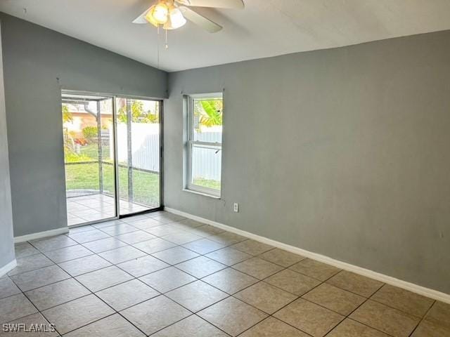 empty room with light tile patterned floors, ceiling fan, baseboards, and vaulted ceiling