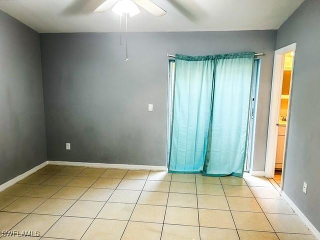 unfurnished room featuring ceiling fan, baseboards, and light tile patterned floors