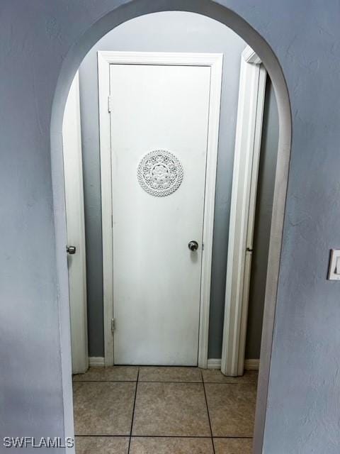 hall with light tile patterned floors and arched walkways