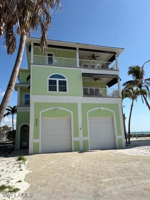 view of front of property featuring a balcony, decorative driveway, ceiling fan, a garage, and stucco siding