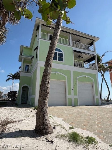view of front of home featuring an attached garage, decorative driveway, and a balcony