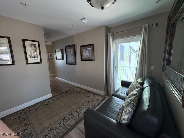 living area with wood finished floors, visible vents, and baseboards