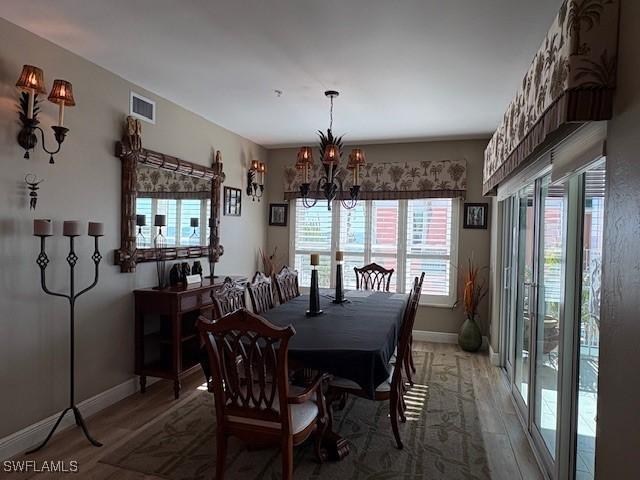 dining space with an inviting chandelier, light wood-type flooring, visible vents, and baseboards