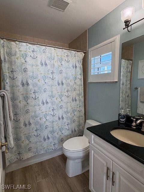 bathroom with toilet, visible vents, wood finished floors, and vanity