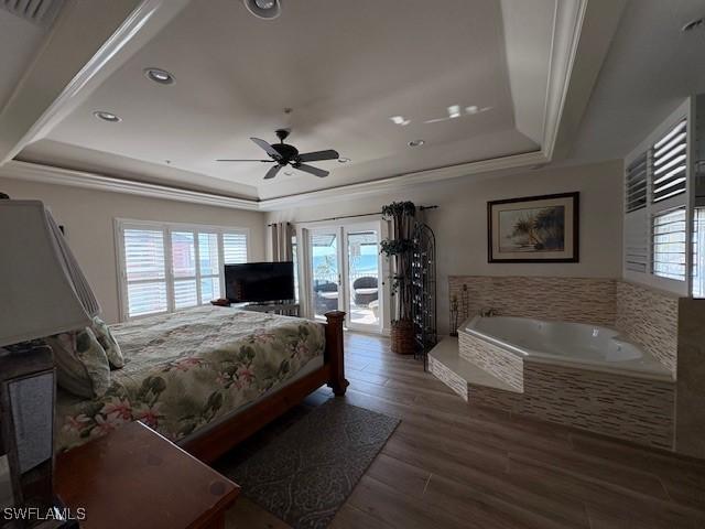 bedroom featuring a raised ceiling, wood finished floors, recessed lighting, and access to exterior