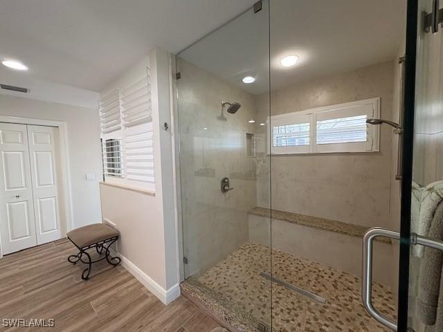 bathroom with a stall shower, baseboards, visible vents, and wood finished floors