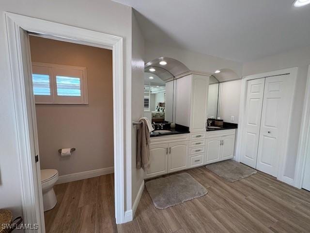 bathroom with recessed lighting, baseboards, toilet, vanity, and wood finished floors