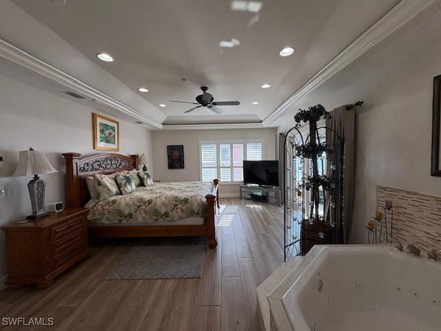 bedroom featuring a raised ceiling, recessed lighting, and wood finished floors