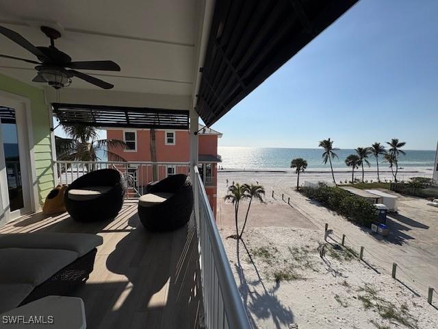 balcony featuring a water view, ceiling fan, and a view of the beach