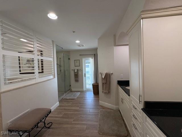 corridor featuring baseboards, visible vents, recessed lighting, and wood finished floors