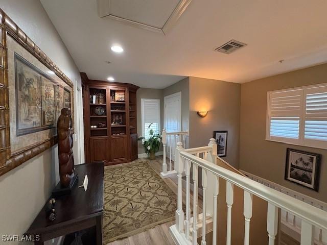 hallway featuring light wood-type flooring, visible vents, an upstairs landing, and recessed lighting