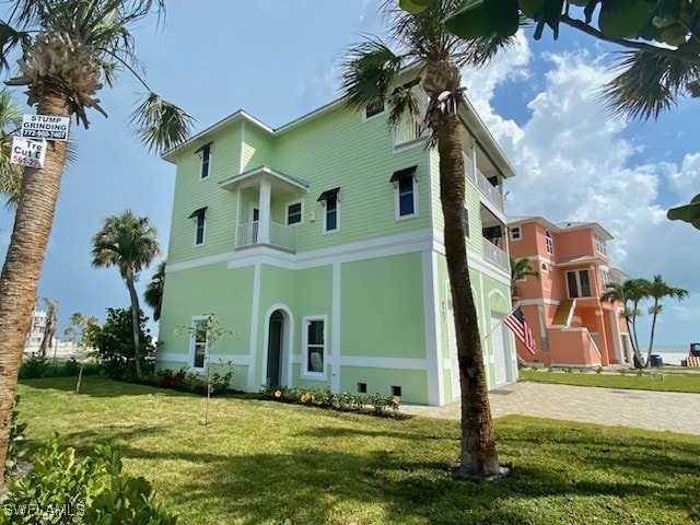 view of front of house featuring stucco siding, driveway, a front yard, and a balcony