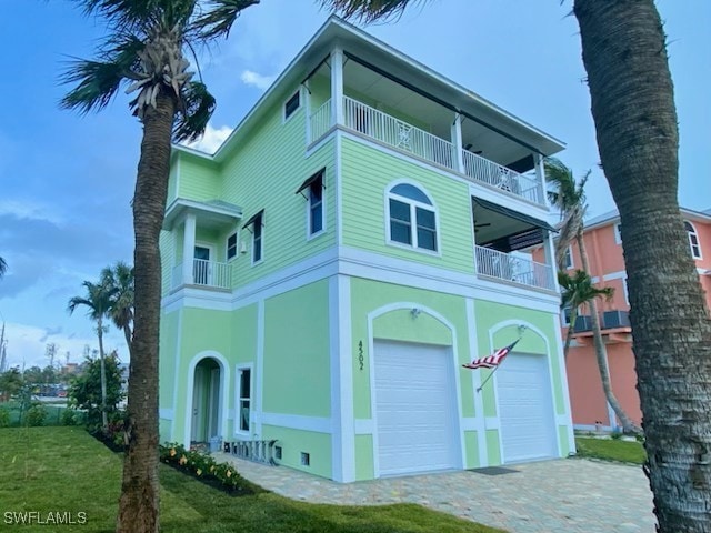 view of front of house with a front yard, an attached garage, driveway, and a balcony