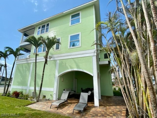 back of property with a yard, a patio area, and stucco siding