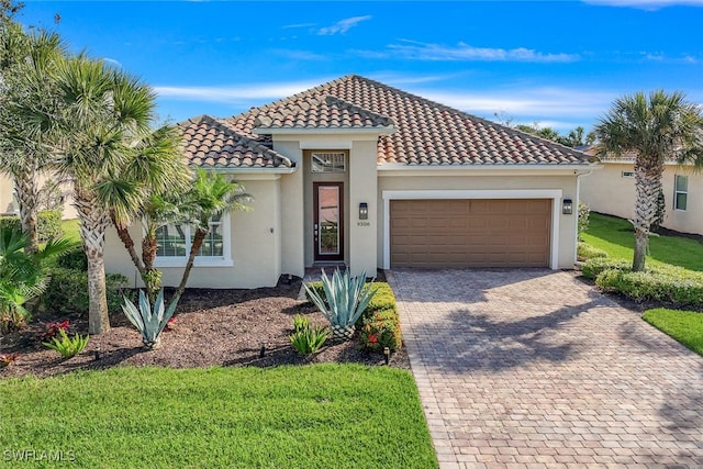 mediterranean / spanish-style home with a tile roof, an attached garage, decorative driveway, a front lawn, and stucco siding