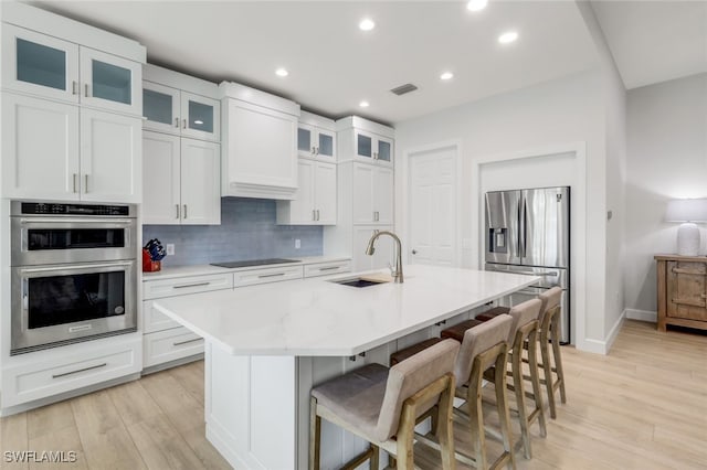 kitchen featuring visible vents, decorative backsplash, a breakfast bar area, appliances with stainless steel finishes, and a sink