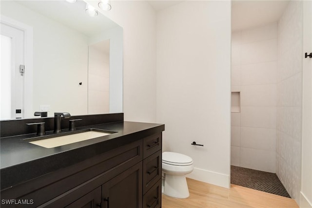 full bathroom featuring toilet, walk in shower, wood finished floors, and vanity