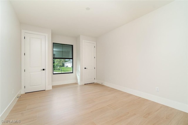 spare room featuring light wood-type flooring and baseboards