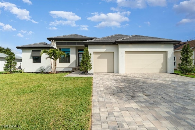 prairie-style house featuring a garage, decorative driveway, a front lawn, and stucco siding