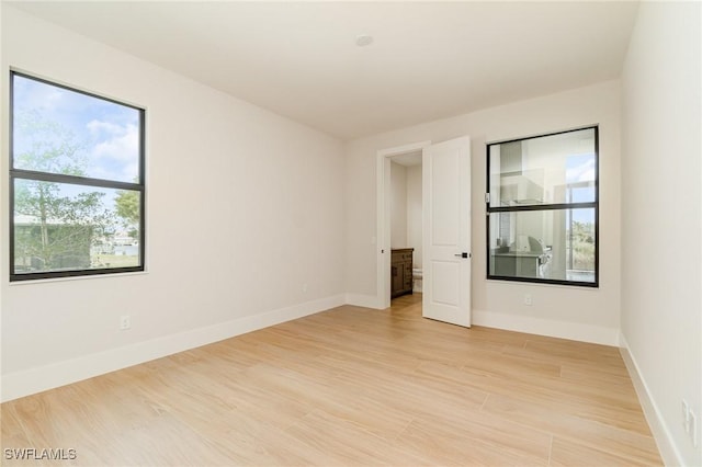 empty room with plenty of natural light, light wood-style flooring, and baseboards