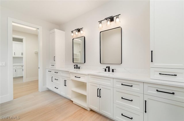 full bathroom featuring wood finished floors, a sink, baseboards, and double vanity