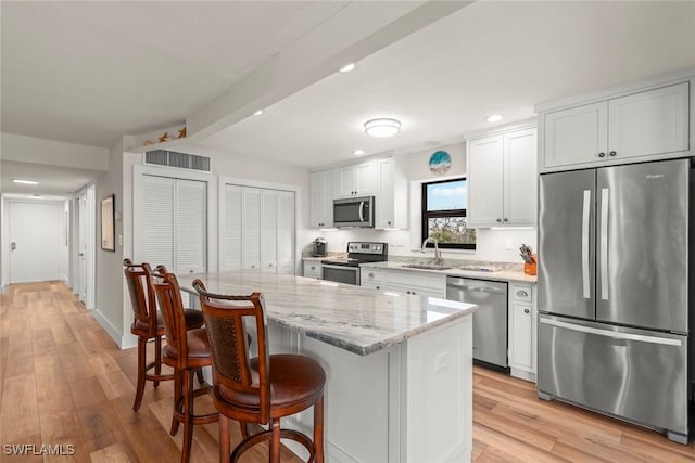 kitchen with light wood-style flooring, a kitchen breakfast bar, stainless steel appliances, and a sink