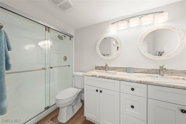 full bathroom featuring visible vents, toilet, wood finished floors, and a sink