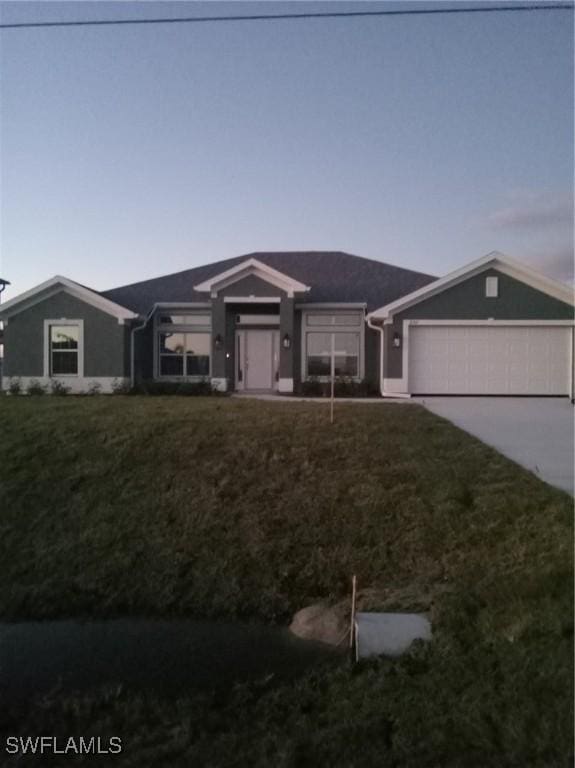 ranch-style house featuring a garage, concrete driveway, and a front lawn