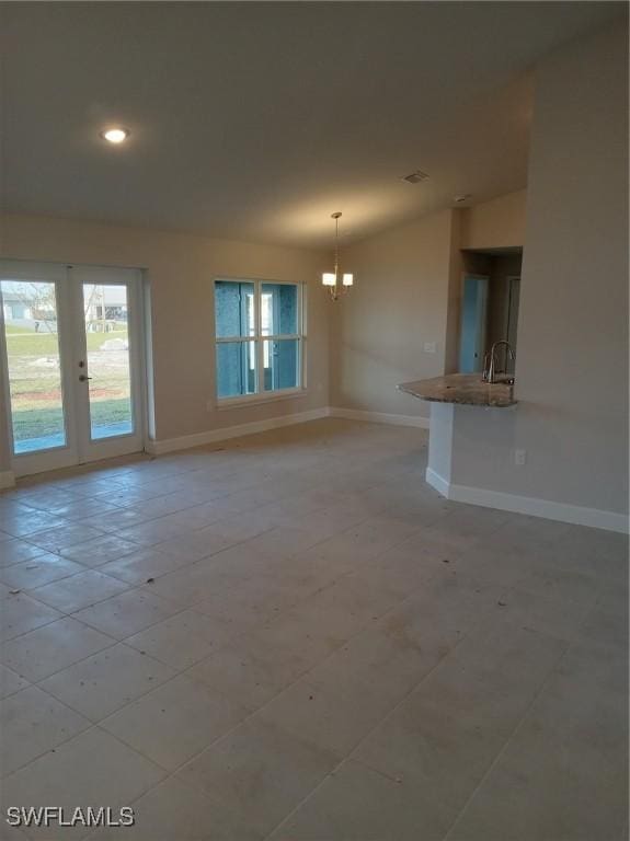 unfurnished living room featuring a notable chandelier, recessed lighting, a sink, and baseboards