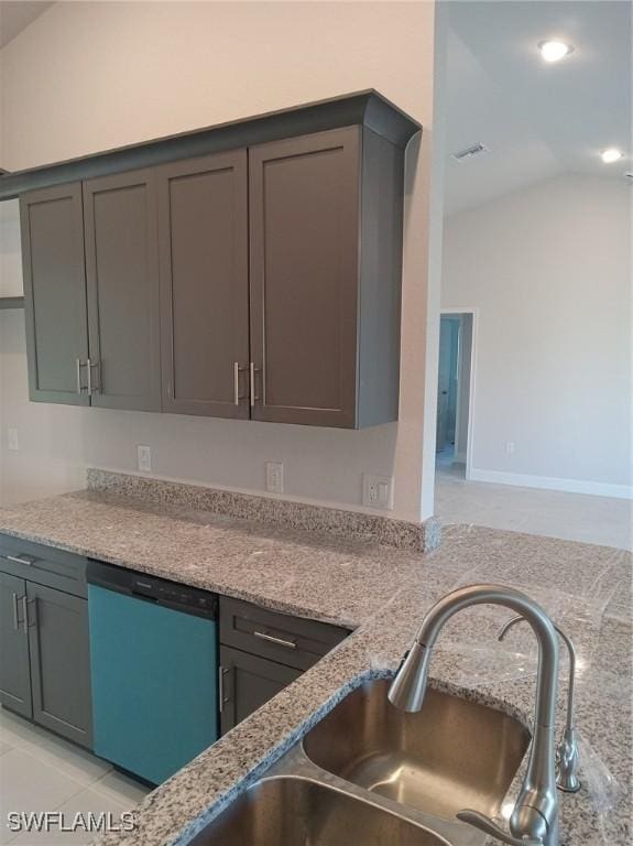 kitchen featuring light stone countertops, dishwashing machine, vaulted ceiling, and a sink