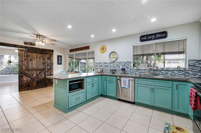 kitchen with a barn door, a sink, appliances with stainless steel finishes, decorative backsplash, and green cabinetry