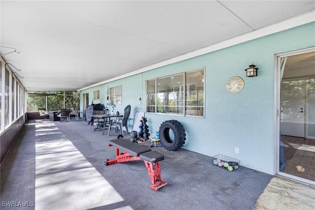 exterior space with a wealth of natural light, a sunroom, carpet flooring, and a textured wall