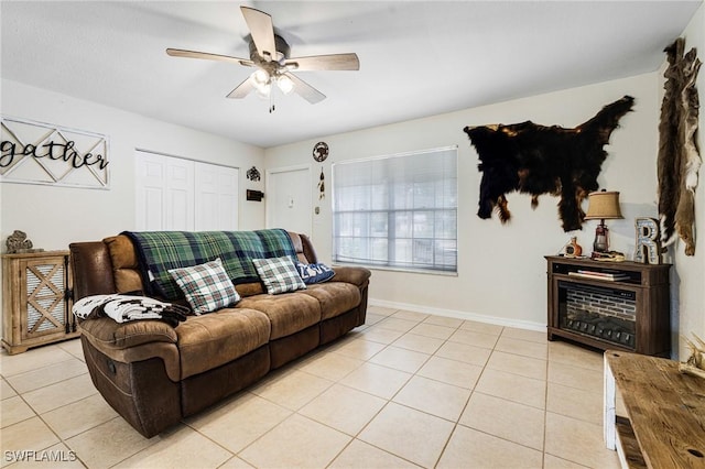 living area with a ceiling fan, light tile patterned flooring, and baseboards