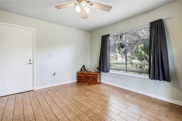 empty room featuring light wood-type flooring, baseboards, and a ceiling fan