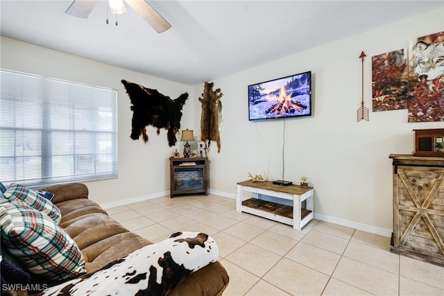 living room with light tile patterned floors, ceiling fan, and baseboards